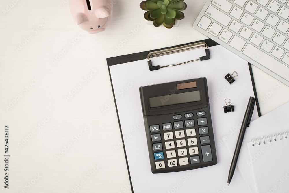 Top view photo of business workplace with keyboard piggy bank plant pen binders notebook papers and calculator on folder on isolated white background with copyspace - obrazy, fototapety, plakaty 