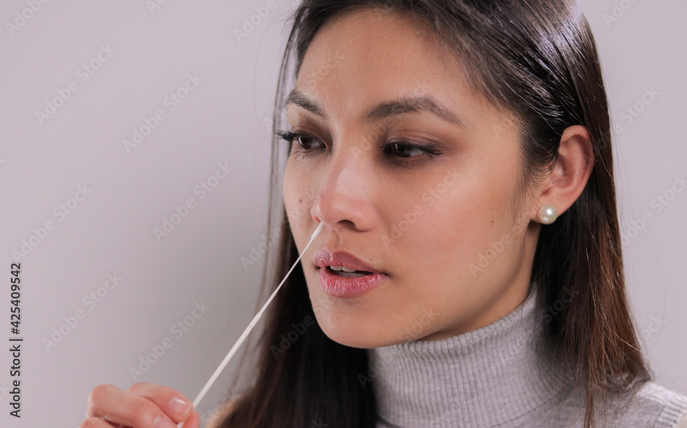 Young woman performs a Covid-19 antigen self-test - studio photography Young woman performs a Covid-19 antigen self-test - studio photography