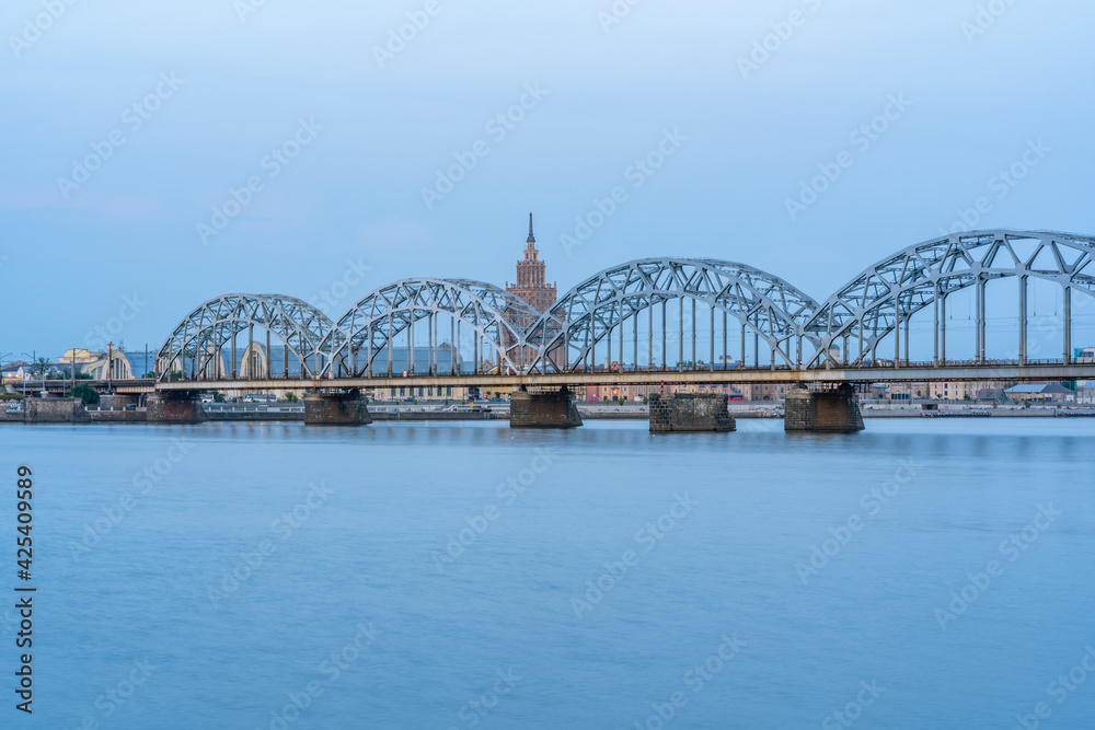 Cityscape with Railway Bridge in Riga, Latvia, on Blue Hour over River Daugava