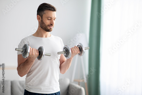 Closeup of handsome bearded man doing dumbbell workout at home