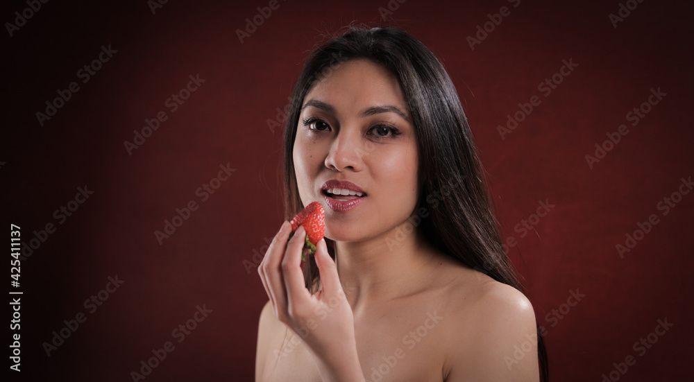 Young pretty woman bites into a strawberry - studio photography Young pretty woman bites into a strawberry - studio photography