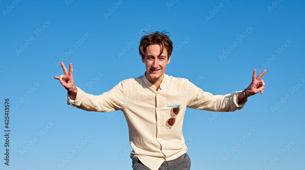 A Caucasian man from Spain making victory signs with both hands on clear sky background A Caucasian man from Spain making victory signs with both hands on clear sky background