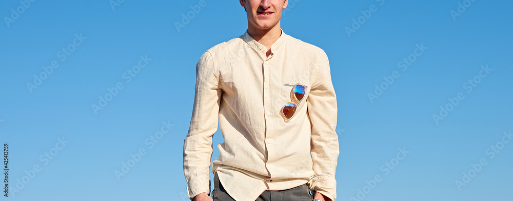 Half body of a young man wearing a beige shirt and sunglasses Half body of a young man wearing a beige shirt and sunglasses