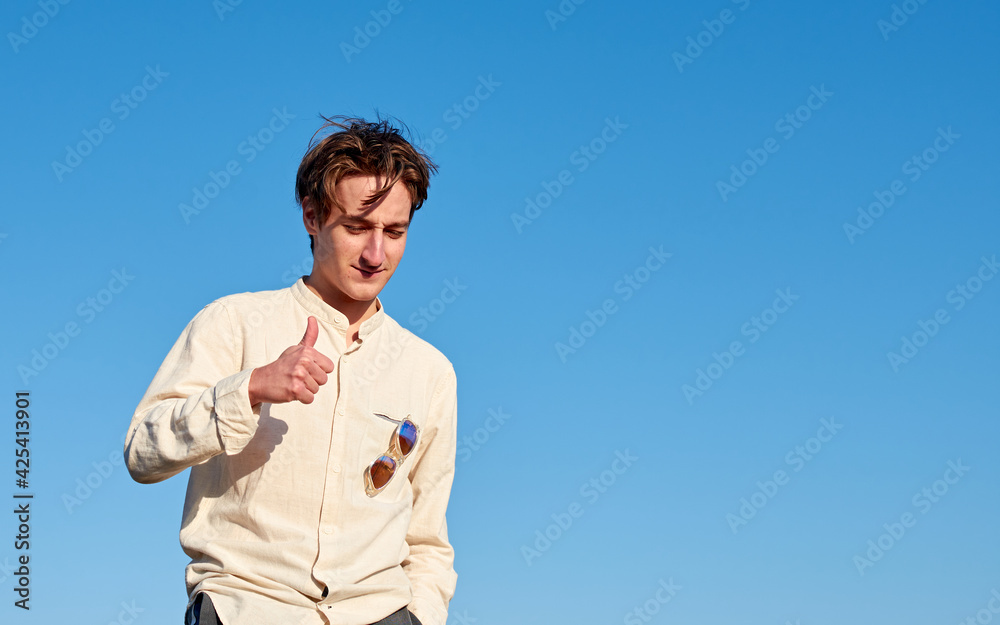 A Caucasian man from Spain making a thumbs up sign on clear sky background A Caucasian man from Spain making a thumbs up sign on clear sky background