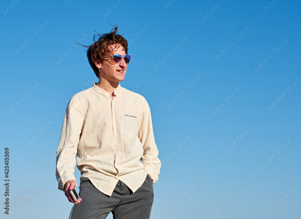 A Caucasian man from Spain holding his phone and staring to his left on clear sky background A Caucasian man from Spain holding his phone and staring to his left on clear sky background