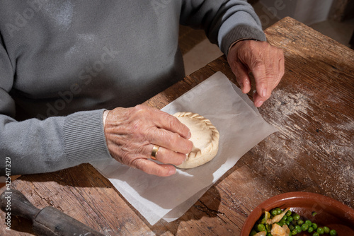 Older woman and young woman making traditional Mallorcan empanadas. Mallorcan empanadas. Easter traditions. Hands doing culinary activities.