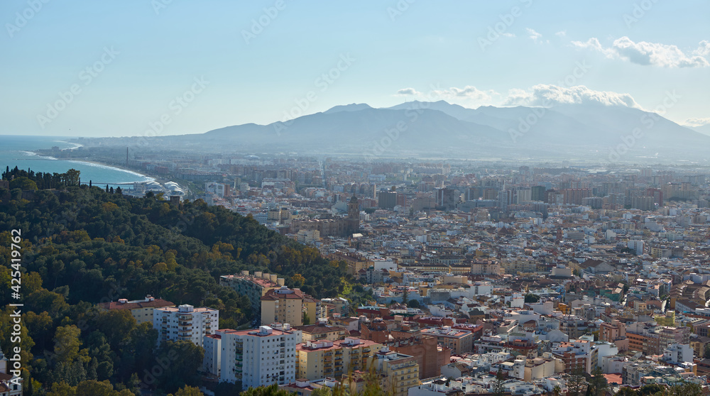 A panoramic shot of a breathtaking view of a coastal town surrounded by incredibly tall and slender mountains