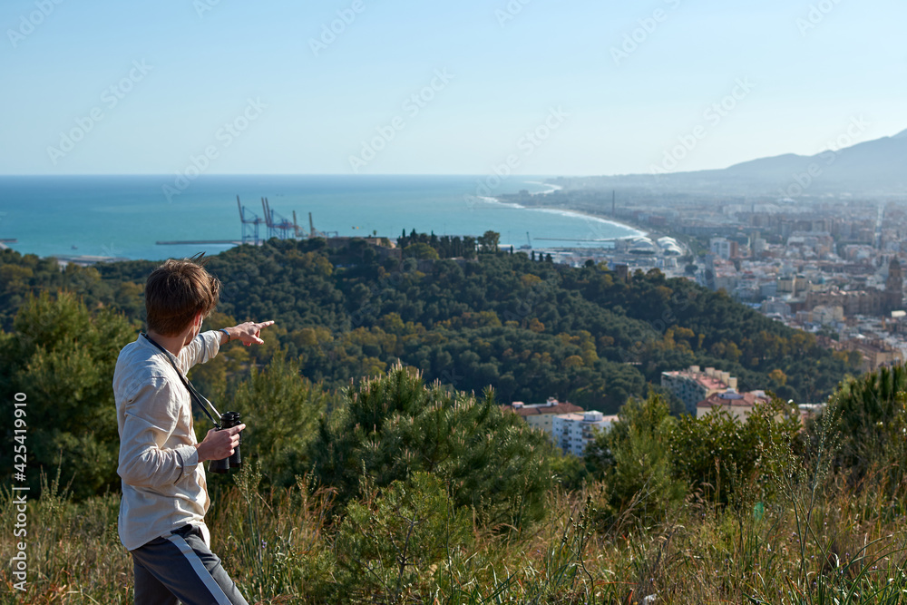 A young caucasian male pointing at a view of the sea from a cliff