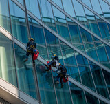 skilled glass cleaners who lower themselves with slings from above