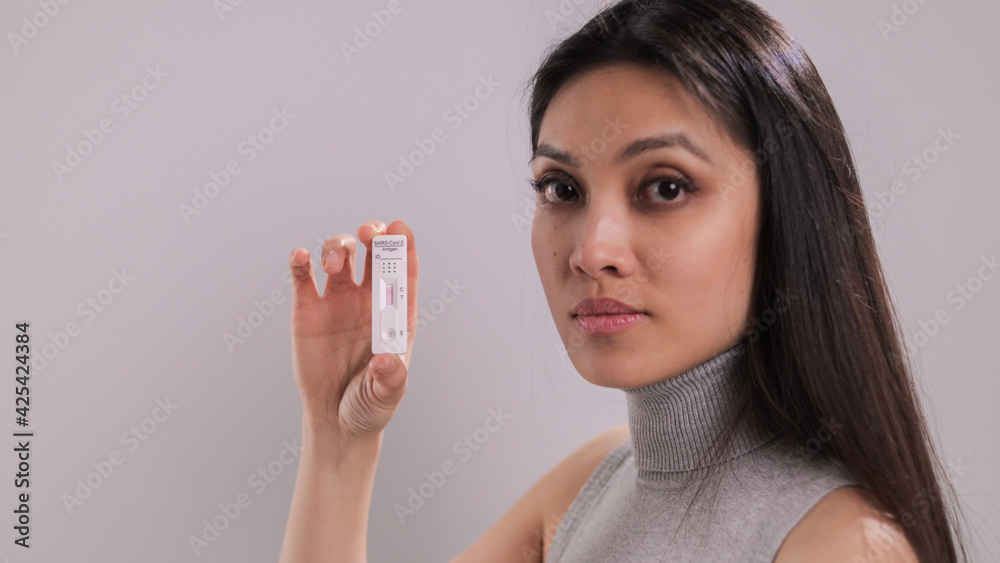 Woman holding a Corona Covid-19 Test with negative result - studio photography Woman holding a Corona Covid-19 Test with negative result - studio photography