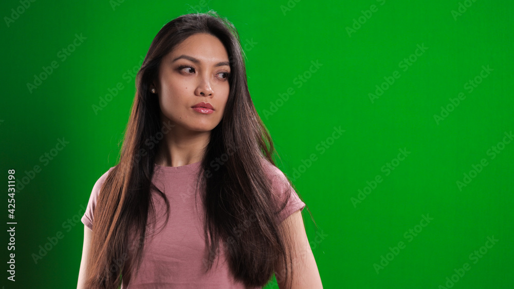 Fototapeta premium Young pretty woman in the studio posing against a green background - studio photography