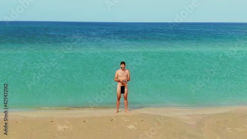 Naked man stay nudist beach. Nudes people naturalist chatting phone ocean shore. Nakedness person summer vacation. Male body nudism. Human staying near sea. using mobile nudity man resort naturalism. photo