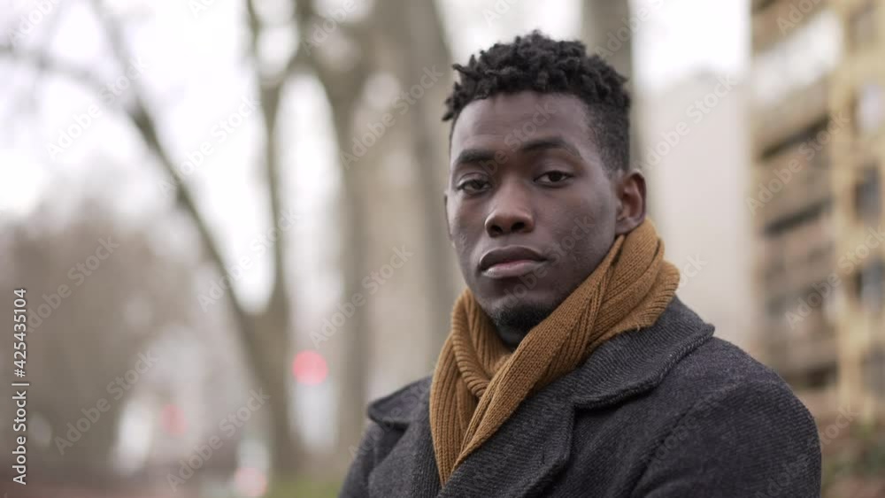 Confident African black man standing outside during winter season portrait staring camera Confident African black man standing outside during winter season portrait staring camera