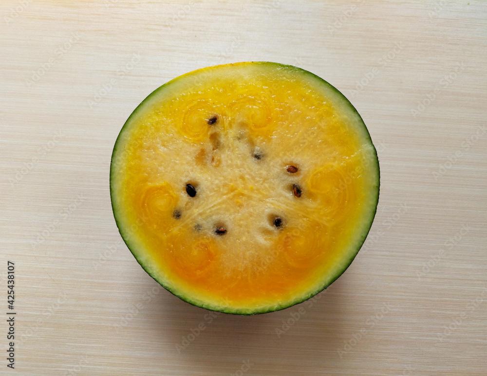 Slice of yellow watermelon on a wooden background