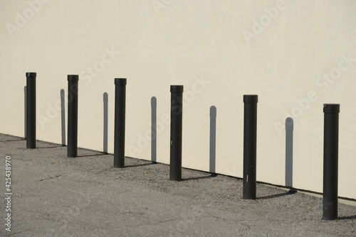 row of black metal posts near a wall