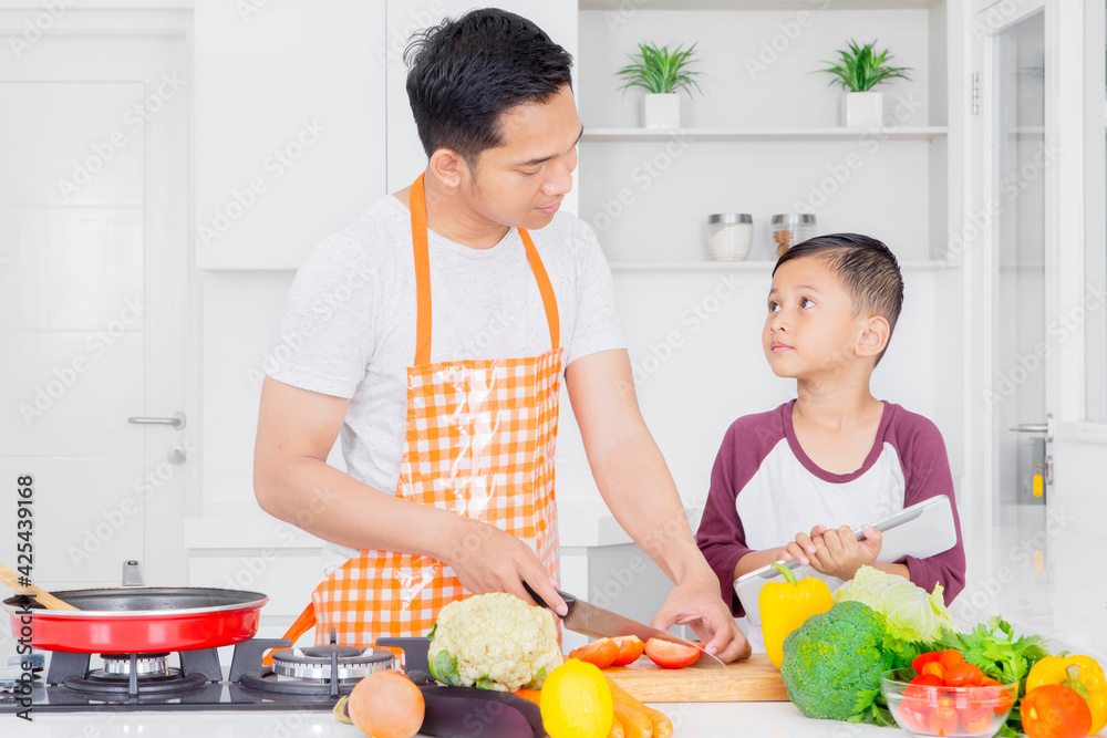 Father chatting with son while cooking in kitchen Father chatting with son while cooking in kitchen