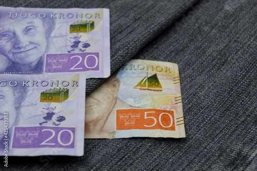 swedish banknotes of different denomination between blue denim fabric