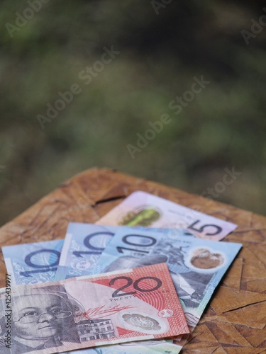 stacked australian banknotes of different denomination on the brown table