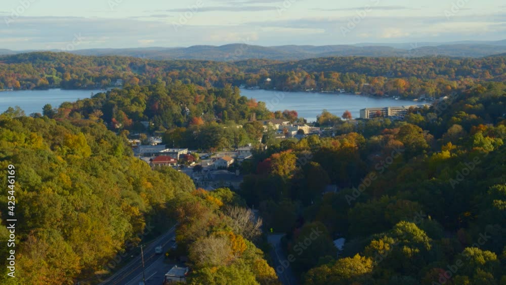 Aerial of country road, settlement and lake amidst autumn forest Aerial of country road, settlement and lake amidst autumn forest