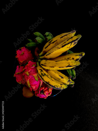 Pitaias maduras e bananas sobre um fundo escuro photo