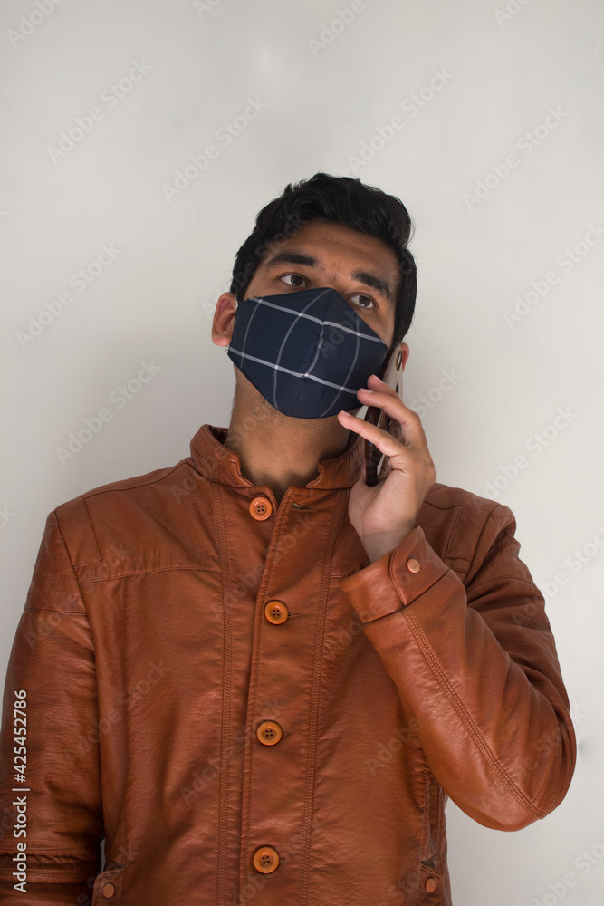 boy listening to a phone call in isolated white background wearing face mask in virus pandemic