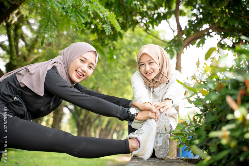 muslim woman friend athlete stretching her leg outdoor together