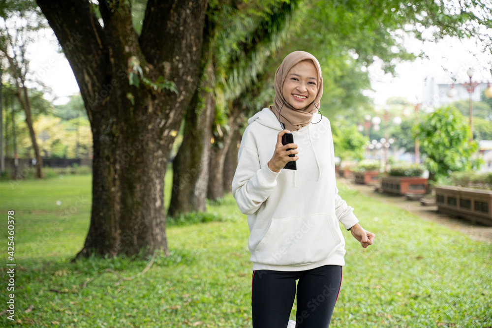 attractive young muslim woman running outdoor. smiling happy asian sport girl jogging attractive young muslim woman running outdoor. smiling happy asian sport girl jogging