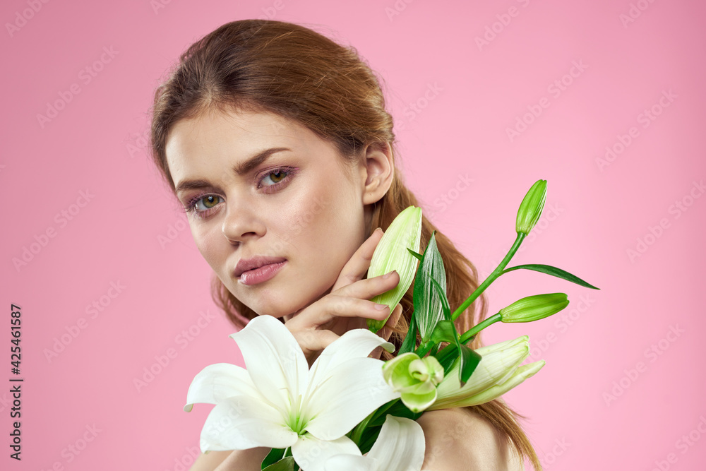 Beautiful woman with flowers on pink background makeup portrait model