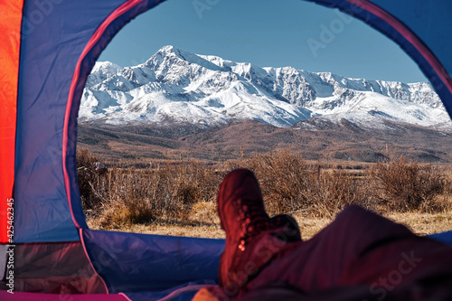 Tent lookout on a Camp in the mountains. Feet Hiker relaxing enjoying view from tent camping entrance outdoor. Travel Lifestyle concept adventure vacations outdoor.