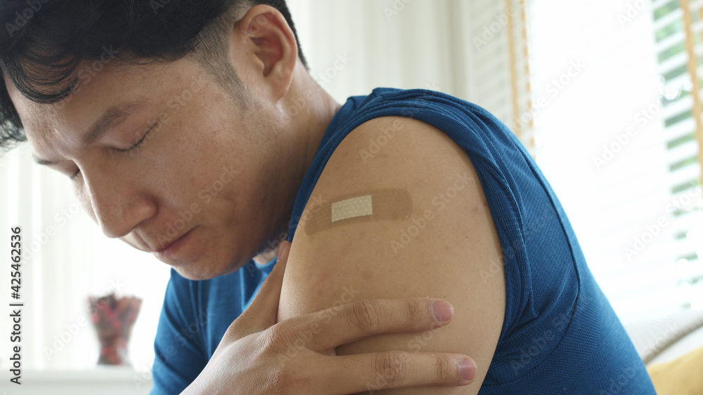 Close up young adult attractive hipster asia man receive covid-19 anti virus vaccine in campaign vaccination safe life got side effect pain at arm. Vaccine rollout swelling in volunteer. - obrazy, fototapety, plakaty 