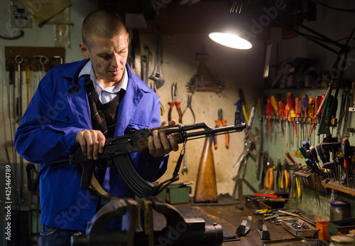Gunsmith with Kalashnikov assault rifle in a weapons workshop