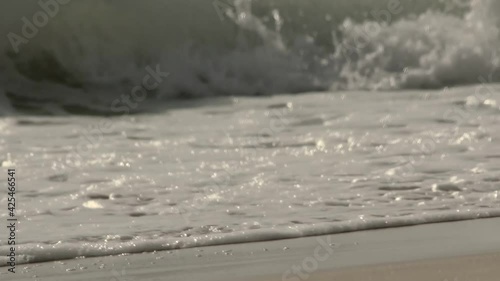 Foamy waves rolling in and break on the shore of Ras Al Jinz Beach in Oman - Detail Long medium tracking shot photo