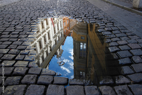 Colorful Buildings and Blue Sky Reflected in Puddle on Cobblestone Street of Prague, Czech Republic
