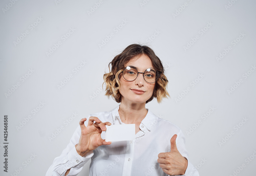 Business woman holding a business card in her hands on a light background mockup
