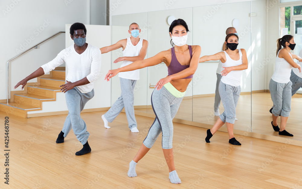 Group of multinational activity people in protective masks practicing dance techniques