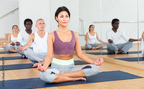 Group of man and woman making yoga meditation in lotus pose at gym