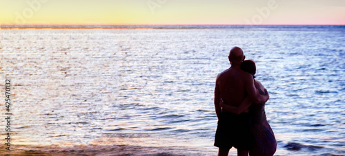 romantic moment of love and live together with silhouette couple of man and woman close hug on seabech in twilight time photo