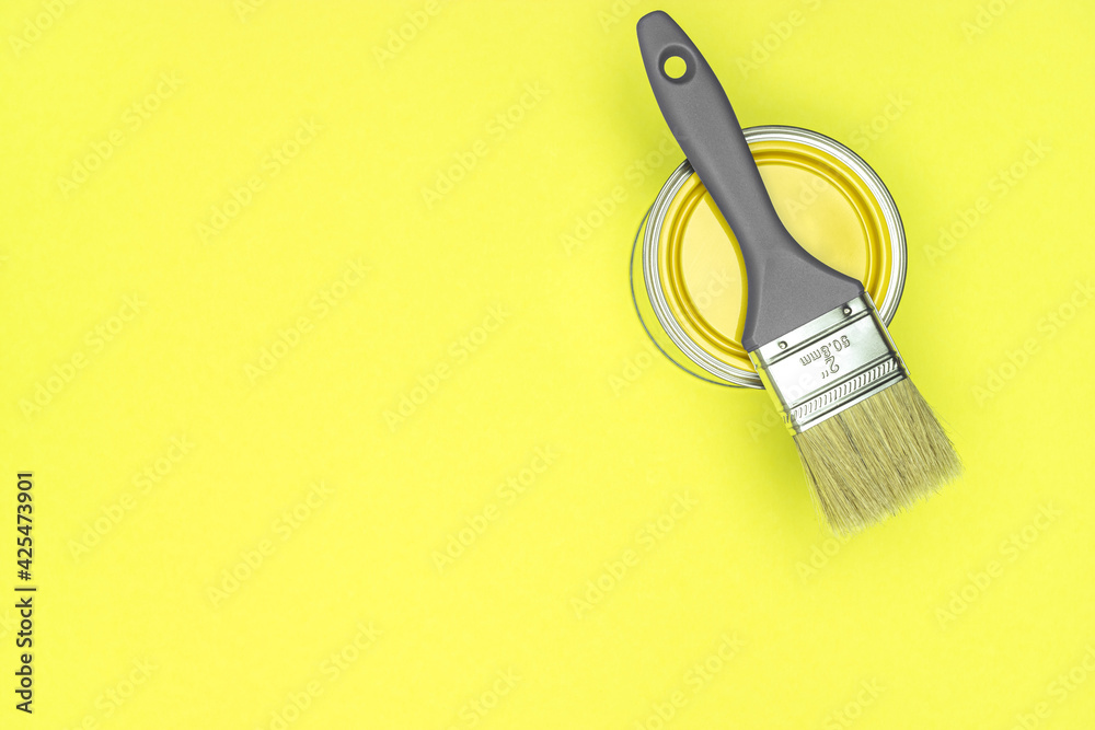 gray paintbrush with can of yellow paint on trendy yellow background. flat lay. gray paintbrush with can of yellow paint on trendy yellow background. flat lay.