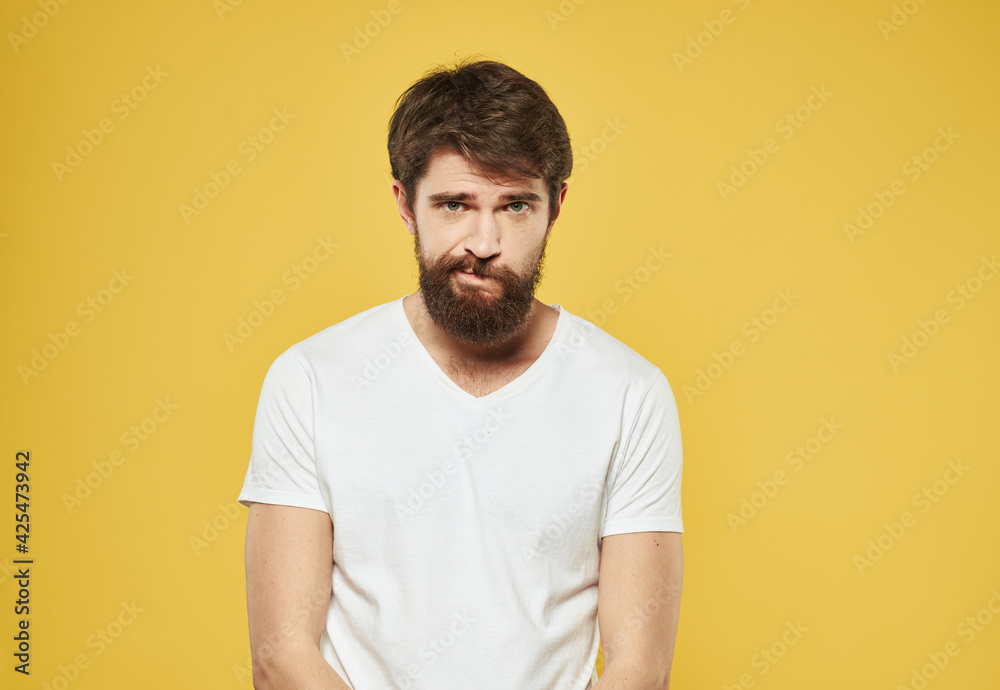 Portrait of a man in a white t-shirt cropped view yellow background puzzled look model Portrait of a man in a white t-shirt cropped view yellow background puzzled look model