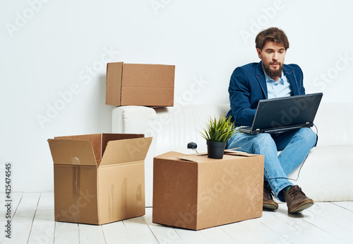 Manager sits on the couch with a laptop working professional boxes with things