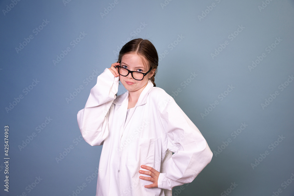 pretty young girl with black glasses and white work lab coat iis posing in front of blue background pretty young girl with black glasses and white work lab coat iis posing in front of blue background