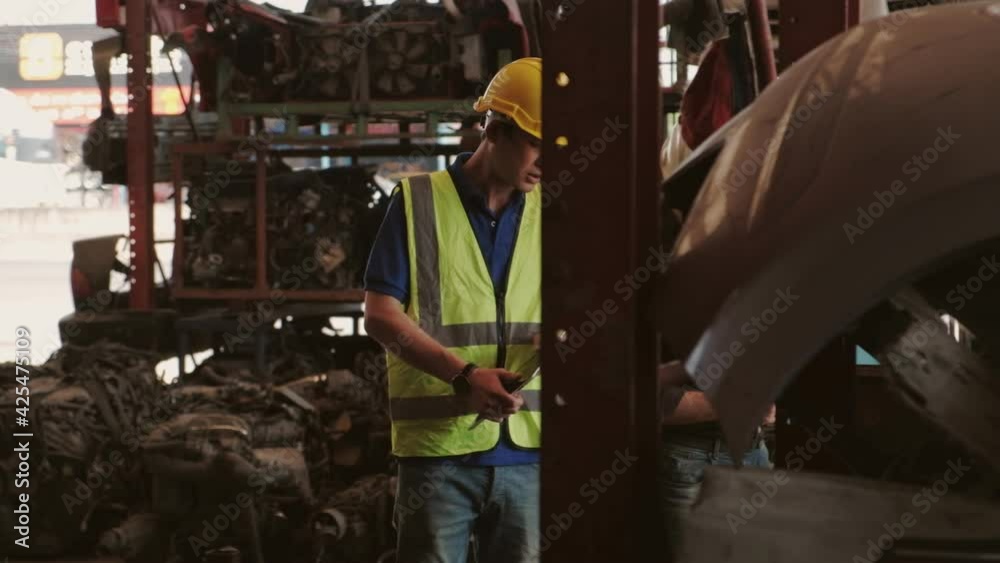 Caucasian Owner & Asian Worker: Two men checking engine parts in a warehouse. With both of them wearing helmets during working time, most of the products are machines In the automobile industry. Caucasian Owner & Asian Worker: Two men checking engine parts in a warehouse. With both of them wearing helmets during working time, most of the products are machines In the automobile industry.