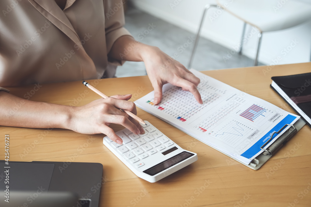 Business woman using calculator to review balance sheet annual using document and laptop computer to calculating budget. audit and Check integrity before investment concept Business woman using calculator to review balance sheet annual using document and laptop computer to calculating budget. audit and Check integrity before investment concept