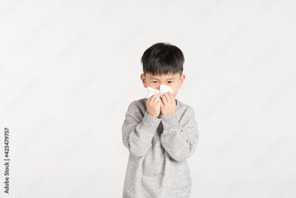 Asian boy holding tissue paper while sneezing or blowing his nose Asian boy holding tissue paper while sneezing or blowing his nose