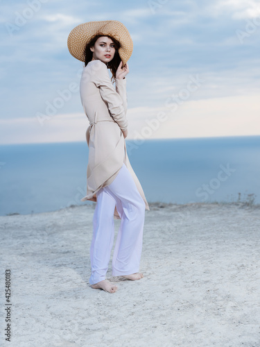 Beautiful woman wearing light clothes on the sand near the ocean in nature