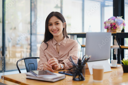 Portrait of woman sitting at her office. Attractive young confident business woman or accountant have idea for her big project.
