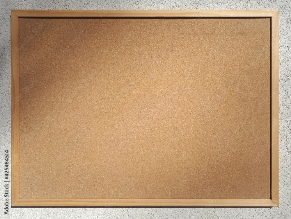 Fototapeta premium Blank cork board for notices on the wall of a house on a sunny day