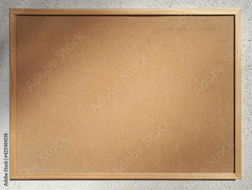 Blank cork board for notices on the wall of a house on a sunny day