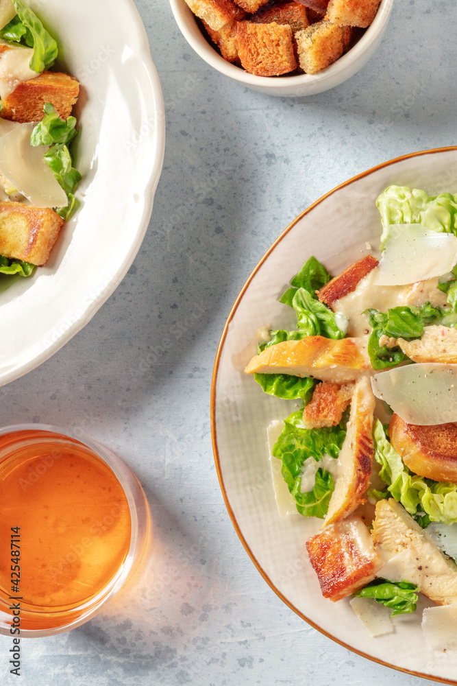 Chicken Caesar salad with wine, overhead shot of two plates Chicken Caesar salad with wine, overhead shot of two plates