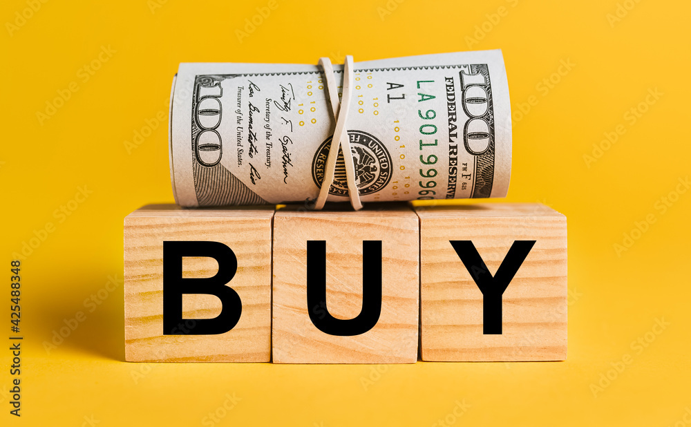 BUY with money on a yellow background. The concept of business, finance, credit, income, savings, investments, exchange, tax